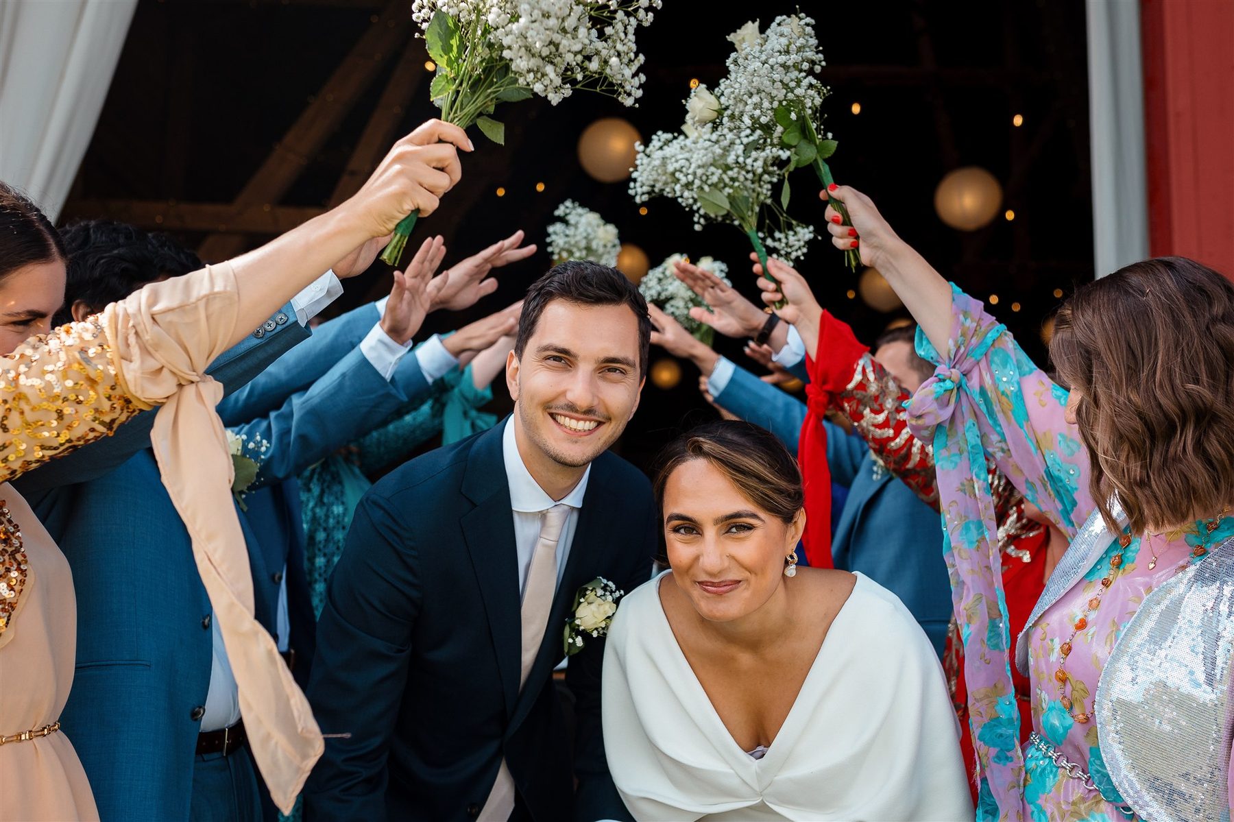 Bröllopspar vid Stallgårdens bröllopsbåge omgiven av blommande buskar